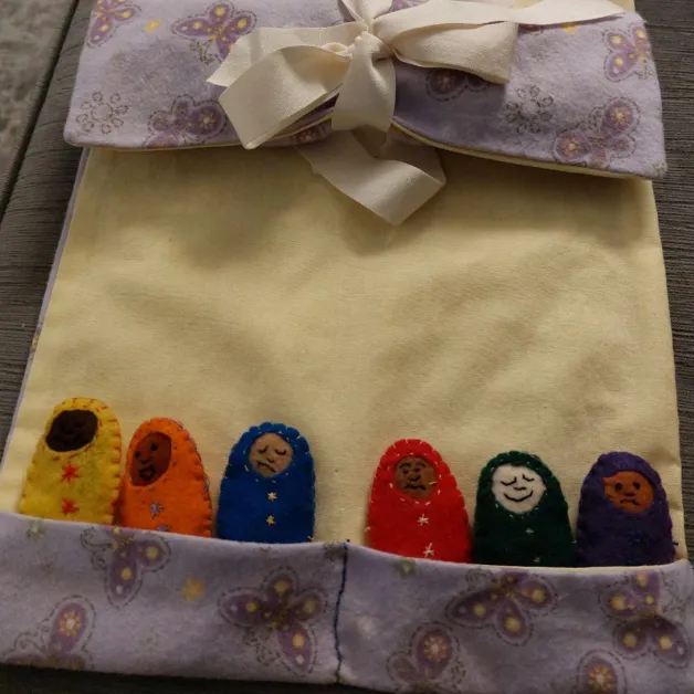 Cloth babies with different expressions tucked in sewn pockets.