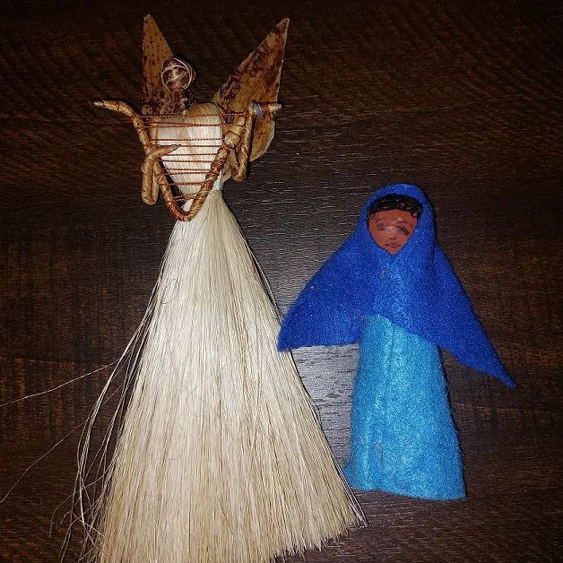 An angel doll holding a stringed instrument, and a Mary doll.