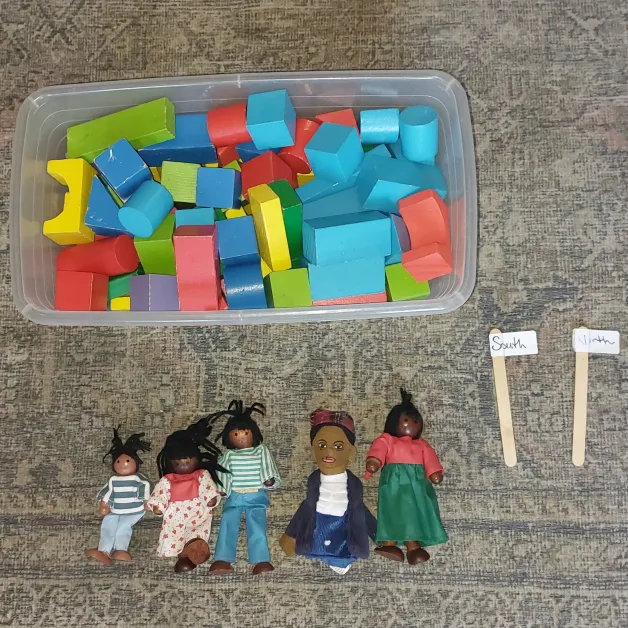 Blocks, North and South signs, and a Harriet Tubman puppet with dollhouse figures.